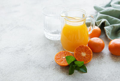Jug of fresh orange tangerine juice with fresh fruits