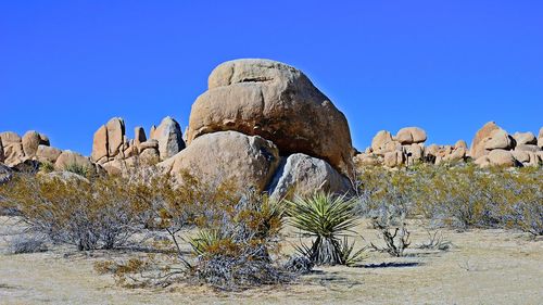 Low angle view of rock formations against clear blue sky