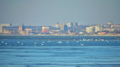 Scenic view of sea by buildings against clear blue sky