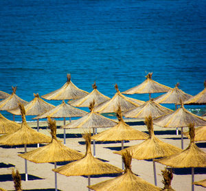 Deck chairs and parasols on beach against blue sea