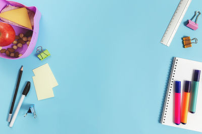 Primary school flat lay concept with assorted school supplies, notepad, pen on blue background