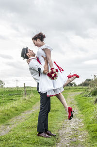 Full length of happy friends standing on field against sky