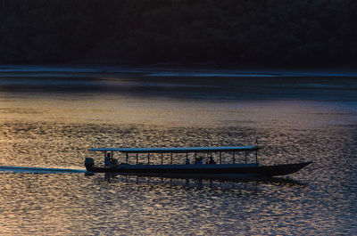 Boat sailing in river at sunset