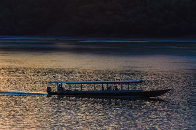 Boat sailing in river at sunset