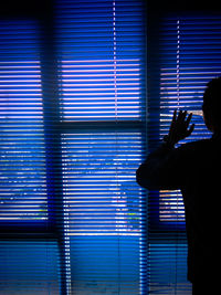 Silhouette man standing by window at night