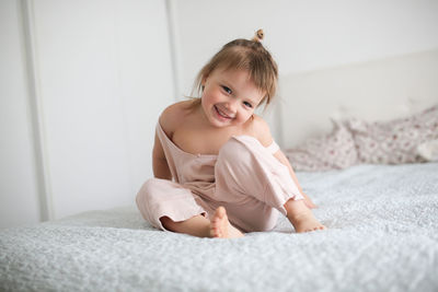 Happy funny girl toddler lifestyle with a smile lying on the bed, close-up, 