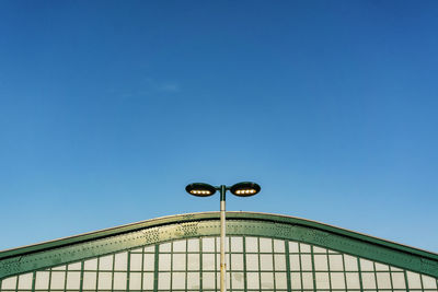 Low angle view of street light by building against blue sky