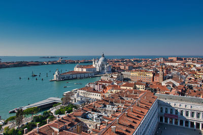 High angle view of townscape by sea against clear blue sky
