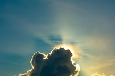 Low angle view of sunlight streaming through clouds