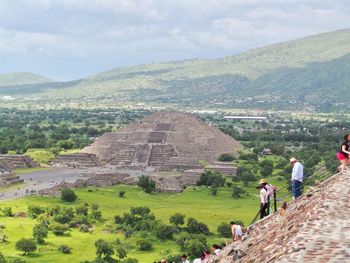 People on steps in front of old ruins against cloudy sky