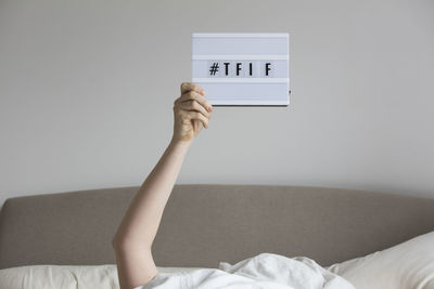 Portrait of person with arms raised on bed against wall at home