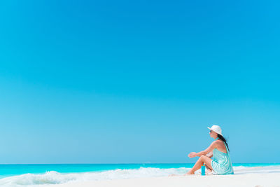 Woman on beach against clear blue sky