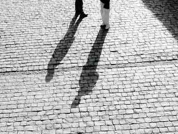 Low section of people walking on cobblestone street