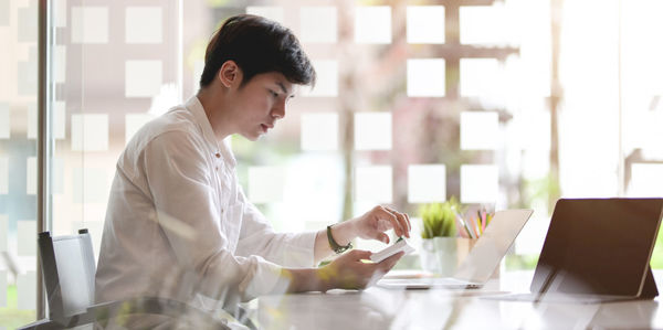 Young woman using phone while sitting on table