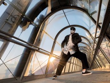 Full length of man in mask dancing at covered elevated walkway