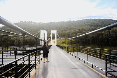 Rear view of man walking on footbridge