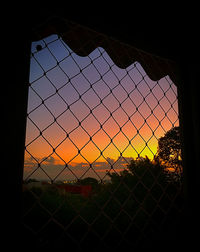 Scenic view of sunset seen through chainlink fence