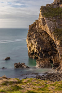 Rock formation on sea shore against sky