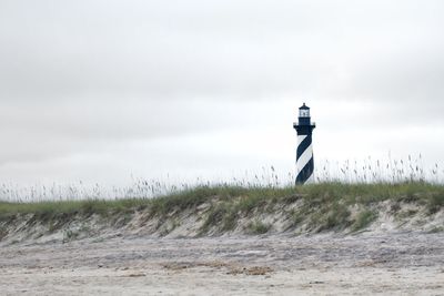 Lighthouse on field against sky