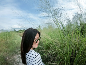 Portrait of young woman looking away on field