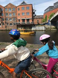 People riding bicycle on canal in city