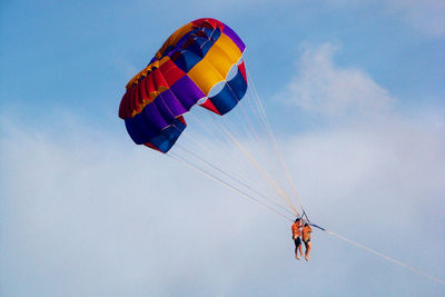 Low angle view of couple parasailing against sky