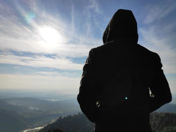 Rear view of silhouette man looking at mountains against sky