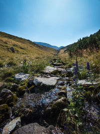 Stream flowing through rocks against sky