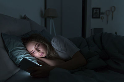 Woman using smart phone while lying on bed