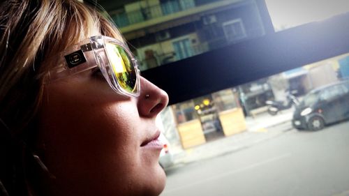 Close-up of woman wearing sunglasses in city