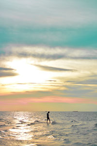 Digital composite image of silhouette man walking on sea at sunset