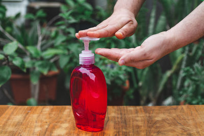 Close-up of hand holding red bottle on table