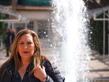 Portrait of woman standing against fountain