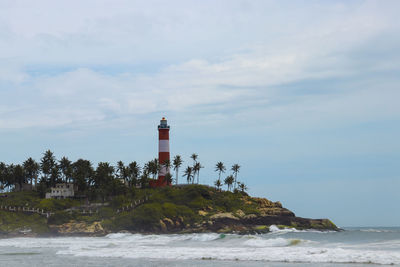 Lighthouse by sea against sky