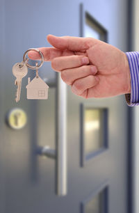 Close-up of man hand holding house key against closed door