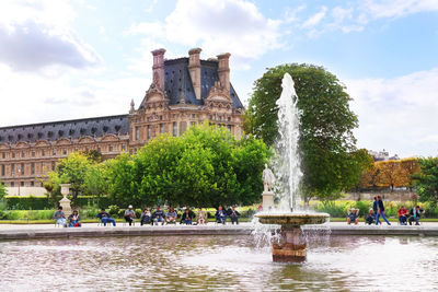 Group of people at fountain in front of building