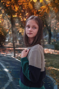 Portrait of young woman standing against trees during autumn