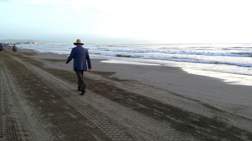 Rear view of man walking on beach