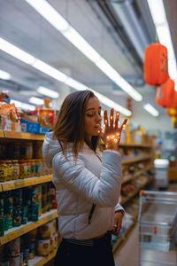 Young woman holding illuminated string light in supermarket