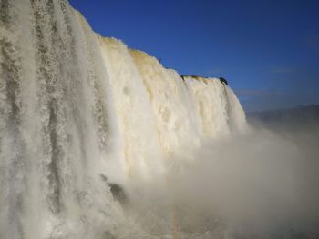 Low angle view of waterfall against clear sky