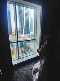 Rear view of woman looking through window