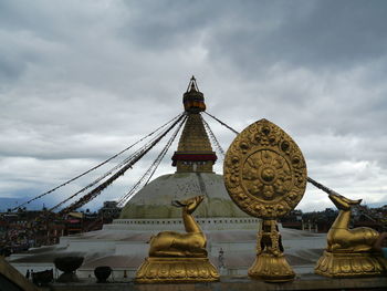 Golden statues at boudhanath against cloudy sky