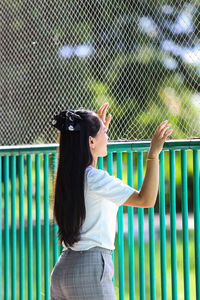 Side view of woman standing against fence