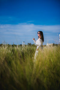 Woman holding umbrella on field against sky
