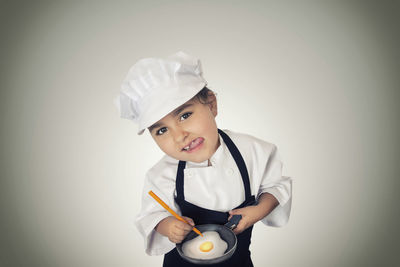 Portrait of smiling boy holding ice cream against white background