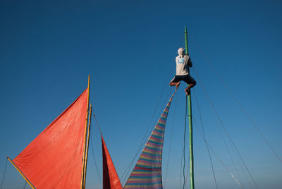 Low angle view of man against clear blue sky