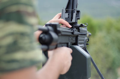 Cropped hand of army aiming gun