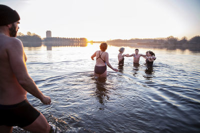 Man looking at male and female friends having fun in water