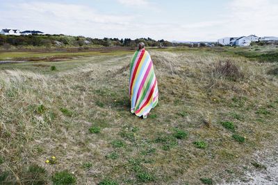 Person with towel on field against sky