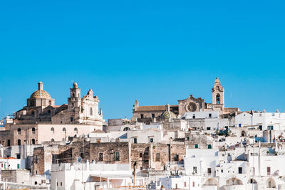 Low angle view of buildings in city against clear blue sky